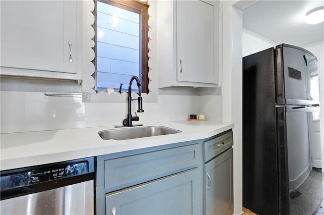 kitchen with dishwasher, light countertops, freestanding refrigerator, and a sink