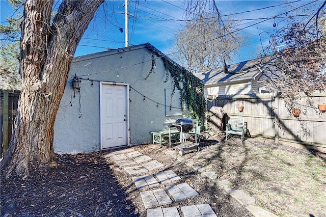 rear view of house with stucco siding and fence