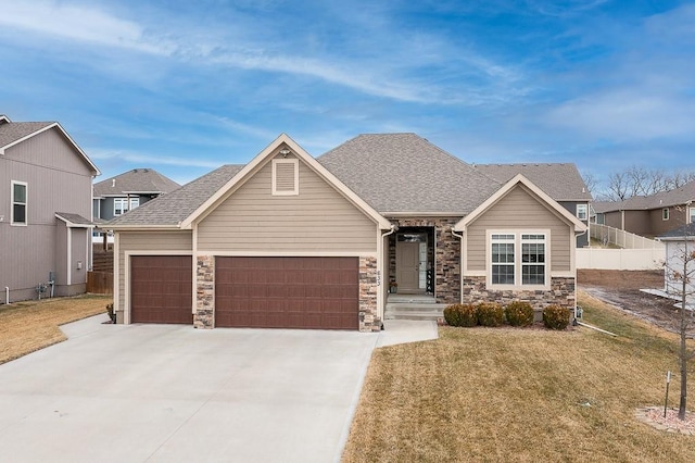 view of front of home featuring a shingled roof, concrete driveway, an attached garage, fence, and a front lawn