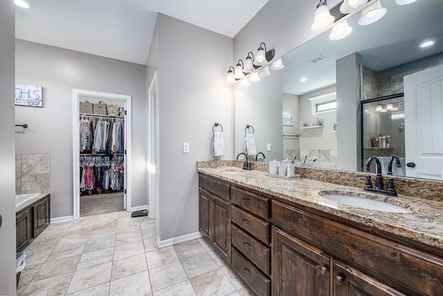 bathroom with baseboards, visible vents, a shower with door, a sink, and a bath