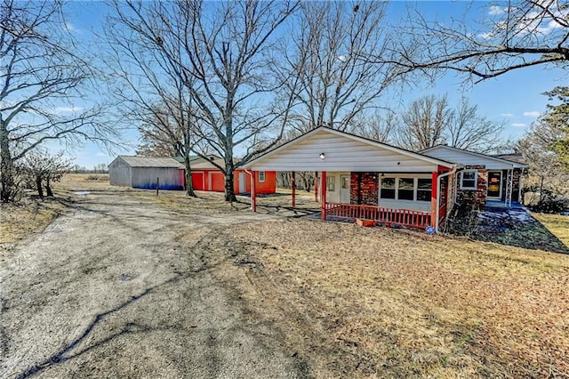 view of front of house featuring a carport, an outdoor structure, and driveway