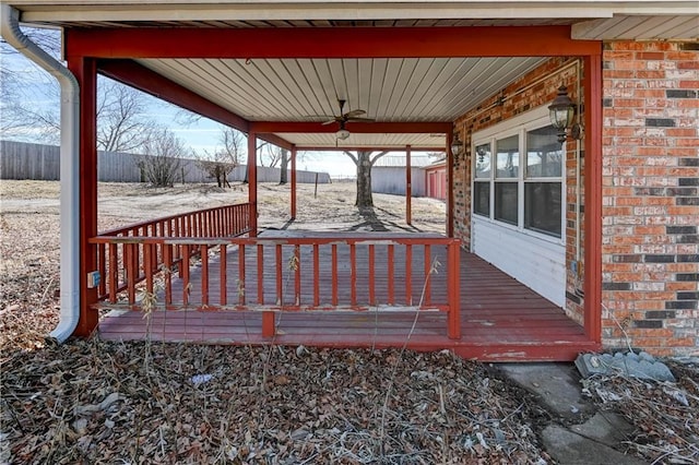 wooden deck featuring a carport, a ceiling fan, and fence