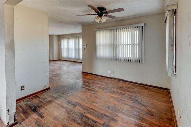 spare room featuring hardwood / wood-style floors, a ceiling fan, visible vents, baseboards, and a textured ceiling