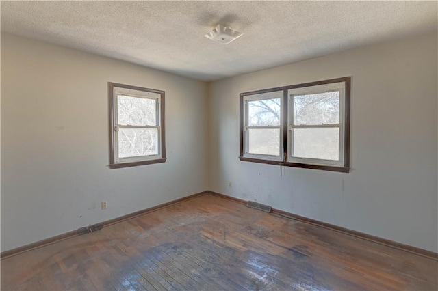 unfurnished room with visible vents, baseboards, a textured ceiling, and hardwood / wood-style floors