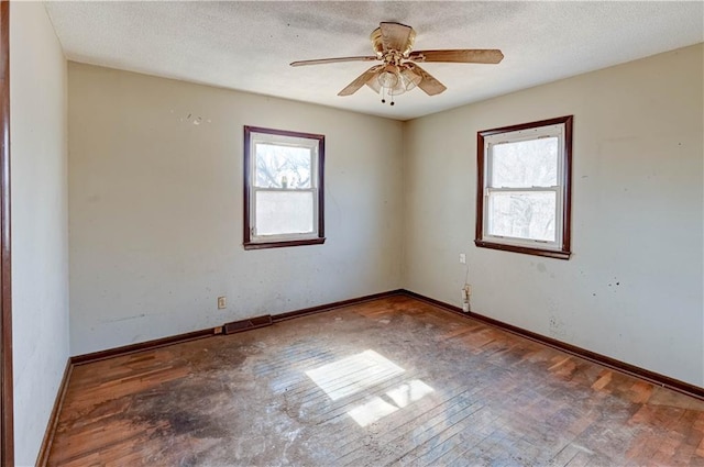 empty room featuring ceiling fan, baseboards, and a textured ceiling