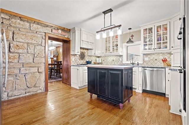 kitchen with white cabinetry, light countertops, light wood-style floors, stainless steel dishwasher, and tasteful backsplash