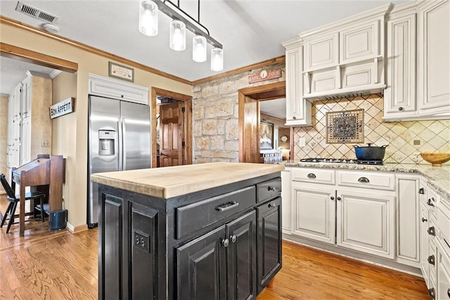 kitchen with visible vents, light wood-style flooring, ornamental molding, dark cabinets, and stainless steel built in refrigerator