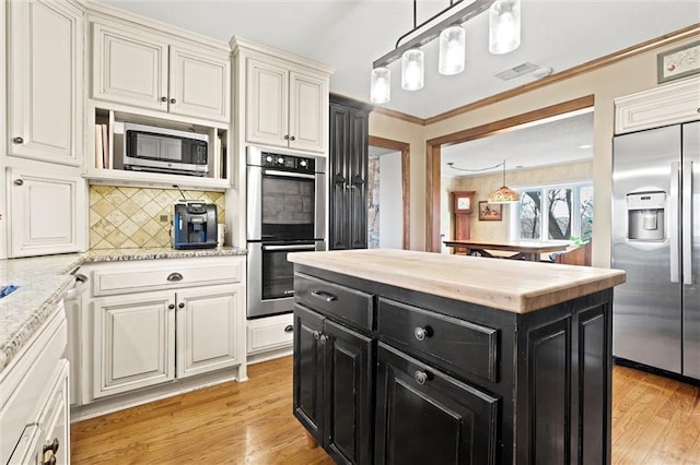 kitchen with dark cabinetry, light wood finished floors, decorative backsplash, light countertops, and built in appliances