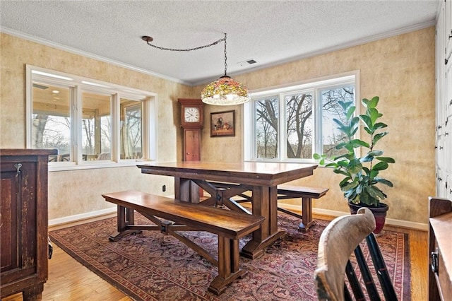 dining area featuring a textured ceiling, a healthy amount of sunlight, crown molding, and light wood finished floors