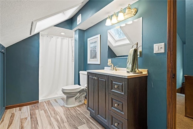 full bathroom with toilet, vanity, vaulted ceiling with skylight, wood finished floors, and a textured ceiling