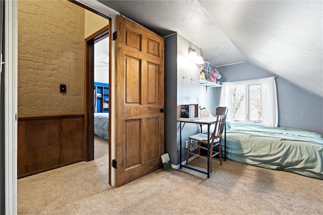 bedroom featuring a textured ceiling, vaulted ceiling, a textured wall, and light carpet