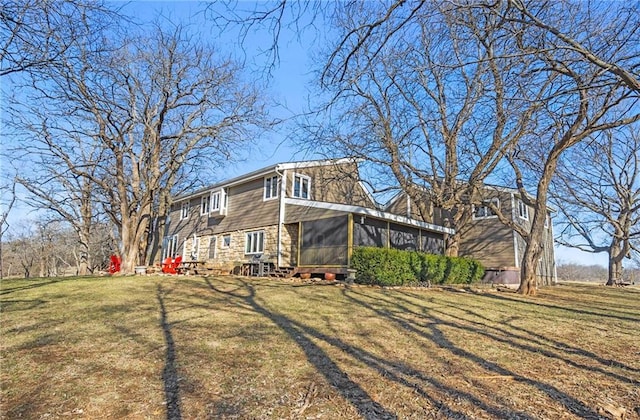 exterior space featuring a yard, stone siding, and a sunroom