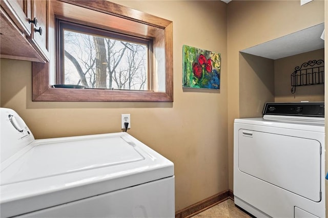 washroom featuring cabinet space, baseboards, and washing machine and clothes dryer