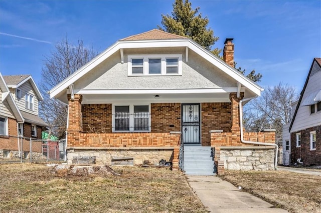 bungalow-style house featuring a chimney, fence, a porch, and brick siding