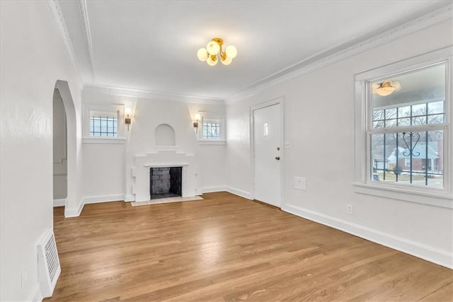 1122 E 76th St, Kansas City, MO 64131 - unfurnished living room featuring arched walkways, a fireplace with flush hearth, visible vents, light wood finished floors, and crown molding