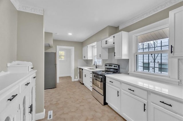 1122 E 76th St, Kansas City, MO 64131 - kitchen with stainless steel appliances, light countertops, decorative backsplash, white cabinets, and a sink