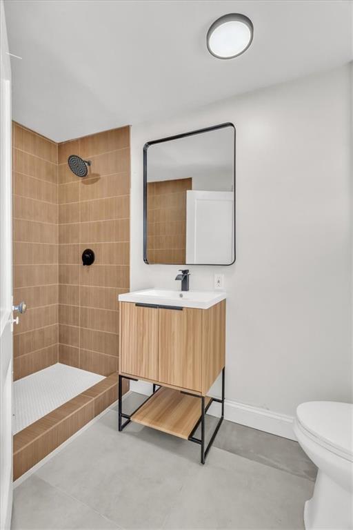 1122 E 76th St, Kansas City, MO 64131 - bathroom featuring tiled shower, vanity, toilet, and baseboards