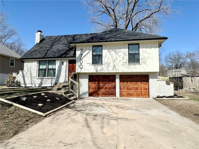 tri-level home featuring board and batten siding, concrete driveway, brick siding, and a chimney