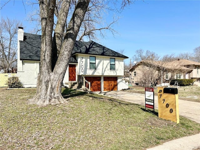 tri-level home with brick siding, an attached garage, entry steps, a chimney, and driveway