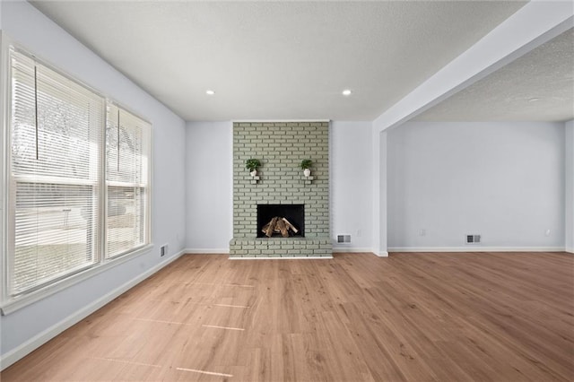 unfurnished living room featuring visible vents, baseboards, light wood-style floors, and a fireplace