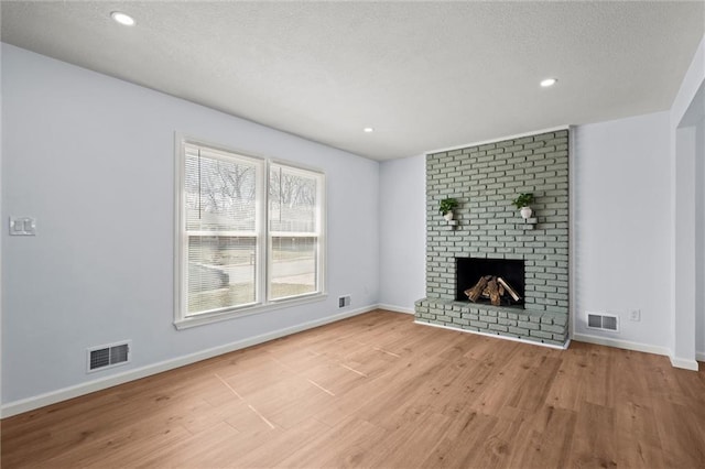 unfurnished living room with visible vents, wood finished floors, and a fireplace