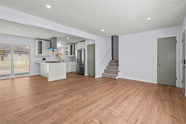 unfurnished living room with recessed lighting, stairway, baseboards, and light wood finished floors