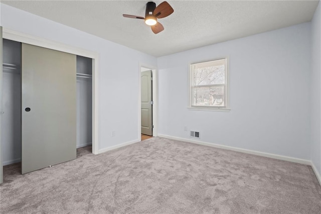 unfurnished bedroom with carpet flooring, visible vents, a closet, and baseboards