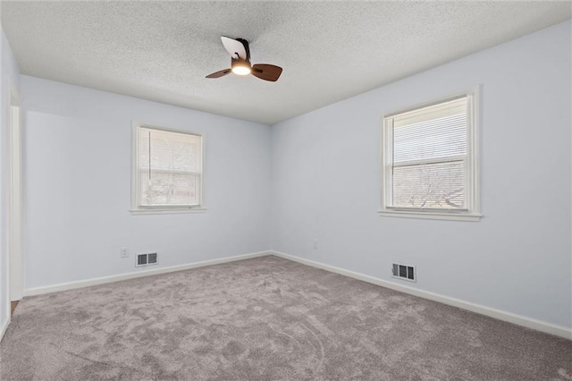 empty room with visible vents, a textured ceiling, baseboards, and carpet floors