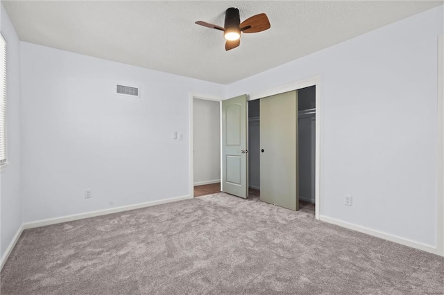 unfurnished bedroom with a ceiling fan, carpet, visible vents, baseboards, and a closet