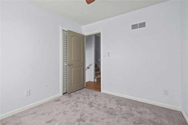 carpeted empty room with visible vents, baseboards, and a textured ceiling