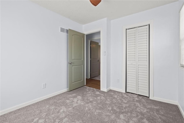 unfurnished bedroom with carpet flooring, baseboards, visible vents, and a closet