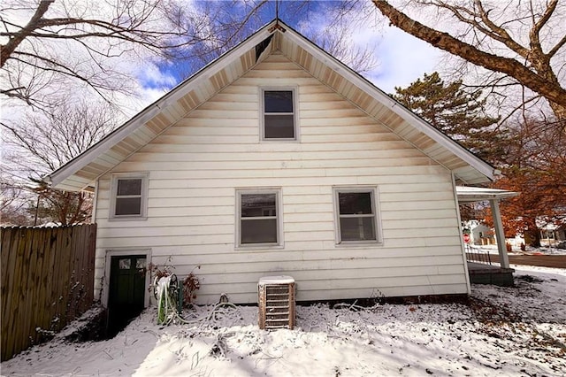 snow covered back of property featuring fence