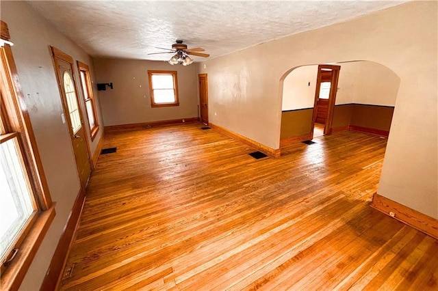 empty room featuring hardwood / wood-style flooring, visible vents, and arched walkways