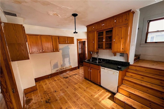 kitchen with a sink, light wood-type flooring, decorative backsplash, dishwasher, and brown cabinetry