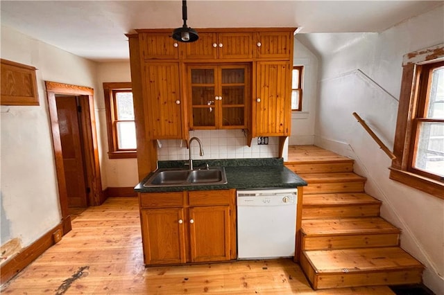 kitchen featuring a sink, light wood-type flooring, decorative backsplash, dishwasher, and brown cabinetry