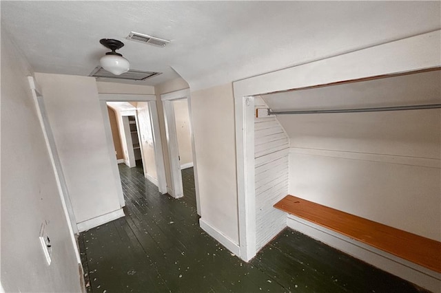 hall featuring baseboards, visible vents, and wood finished floors