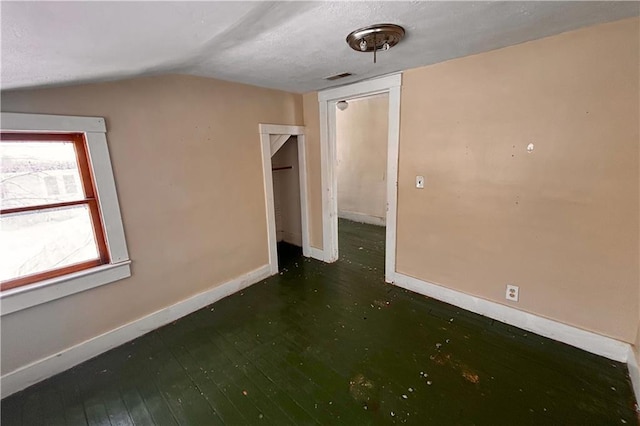 interior space with lofted ceiling, visible vents, hardwood / wood-style flooring, and baseboards