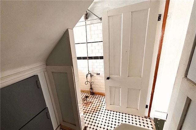 full bath with a tile shower and vaulted ceiling