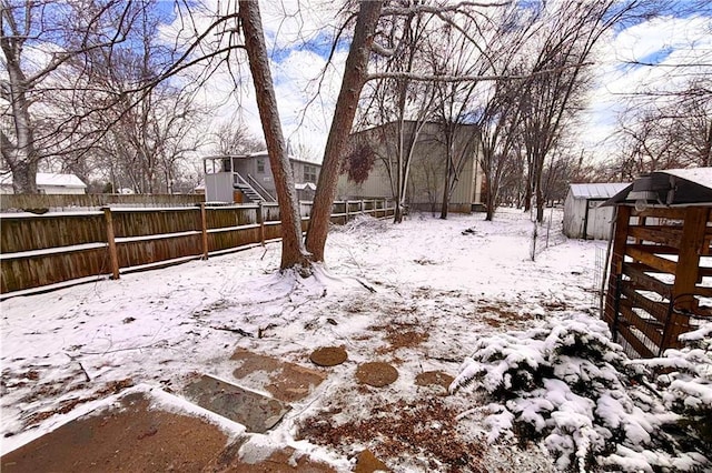 yard layered in snow with fence private yard, an outdoor structure, and a storage unit