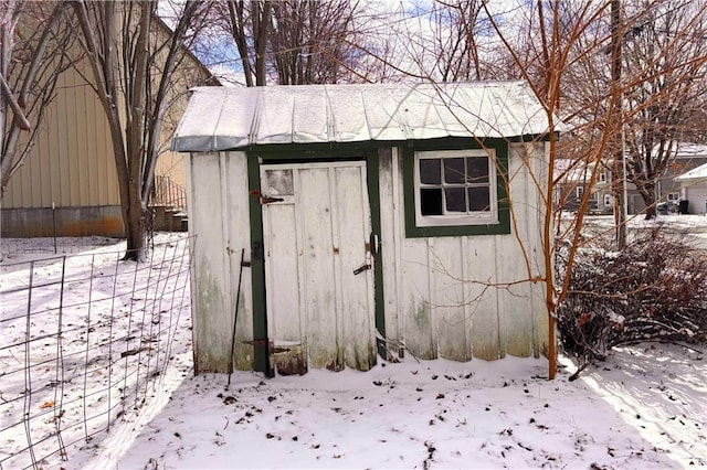 snow covered structure featuring an outbuilding and a storage unit