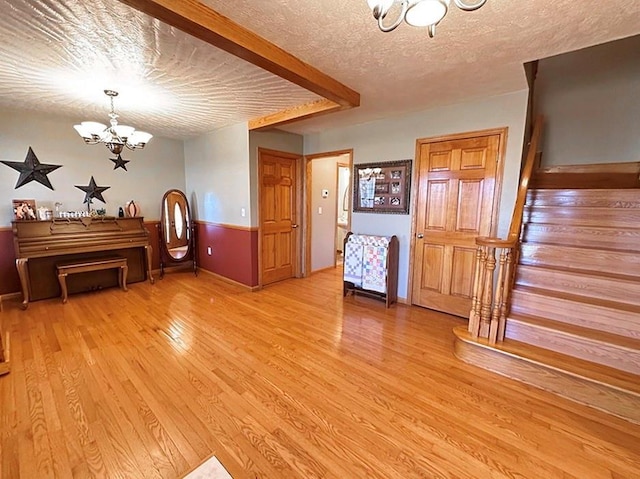 interior space with stairs, a textured ceiling, light wood-type flooring, and an inviting chandelier