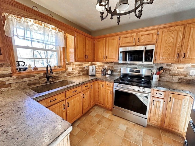 kitchen with a textured ceiling, appliances with stainless steel finishes, decorative backsplash, and a sink