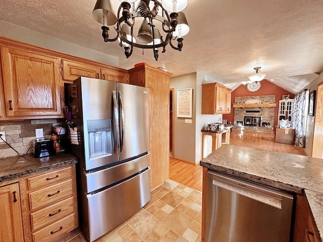 kitchen with open floor plan, an inviting chandelier, stainless steel appliances, a textured ceiling, and backsplash