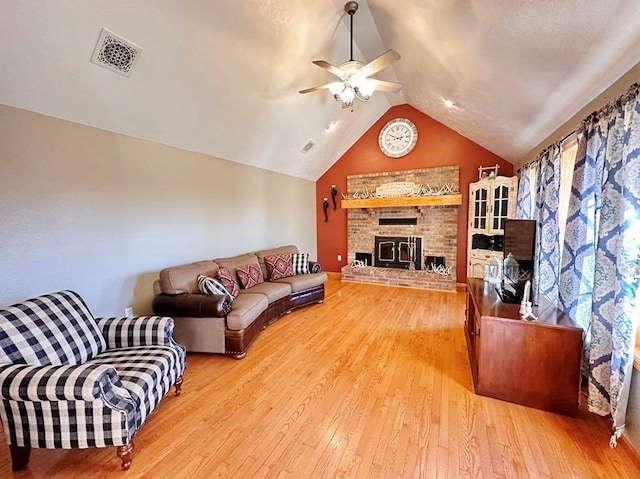 living area with lofted ceiling, hardwood / wood-style floors, visible vents, and a ceiling fan