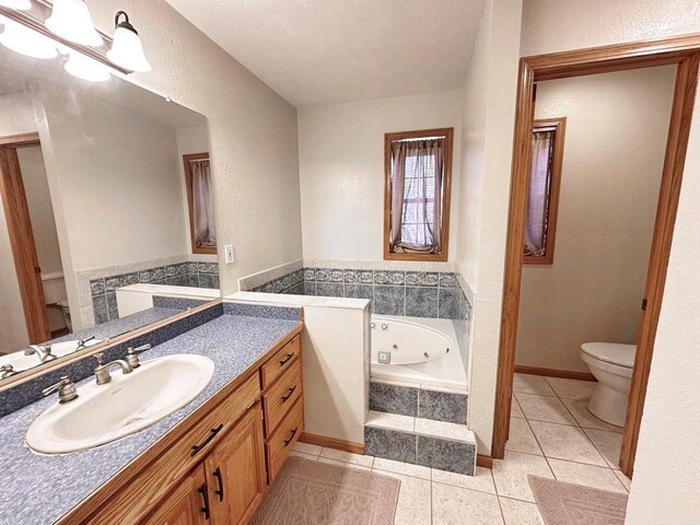 bathroom featuring toilet, a textured ceiling, vanity, tile patterned flooring, and a bath