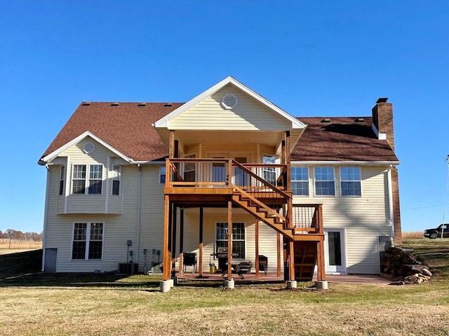 back of house featuring central AC unit, a lawn, a chimney, stairway, and roof with shingles