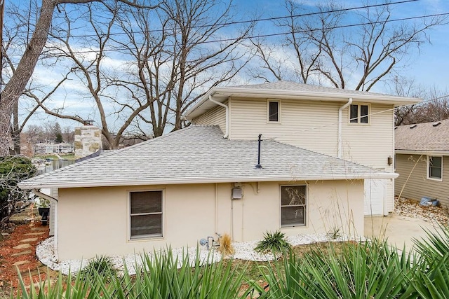 view of side of property featuring stucco siding and roof with shingles