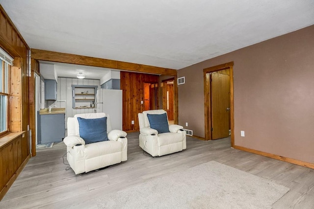 unfurnished room with light wood-type flooring, a sink, visible vents, and baseboards