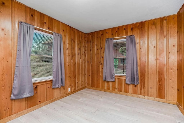 empty room featuring light wood-type flooring and wood walls