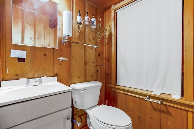 bathroom with wood walls, vanity, and toilet